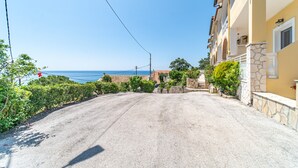 Une route côtière menant à un bâtiment à la façade en pierre, offrant une vue sur la mer.