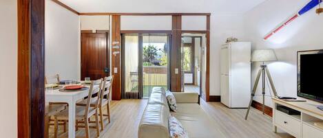 A room with a dining table, chairs, a sofa, a TV, and a tripod.