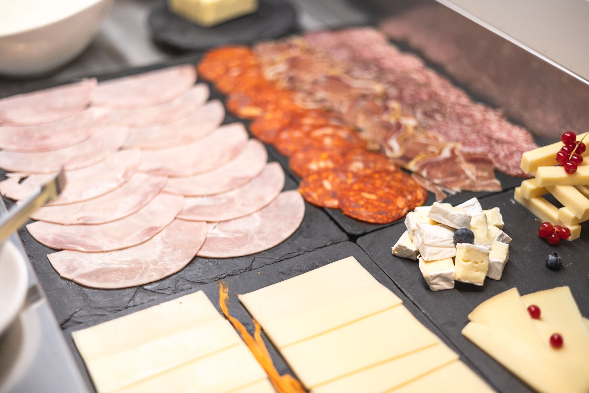 A charcuterie board with various meats, cheeses, and fruits.
