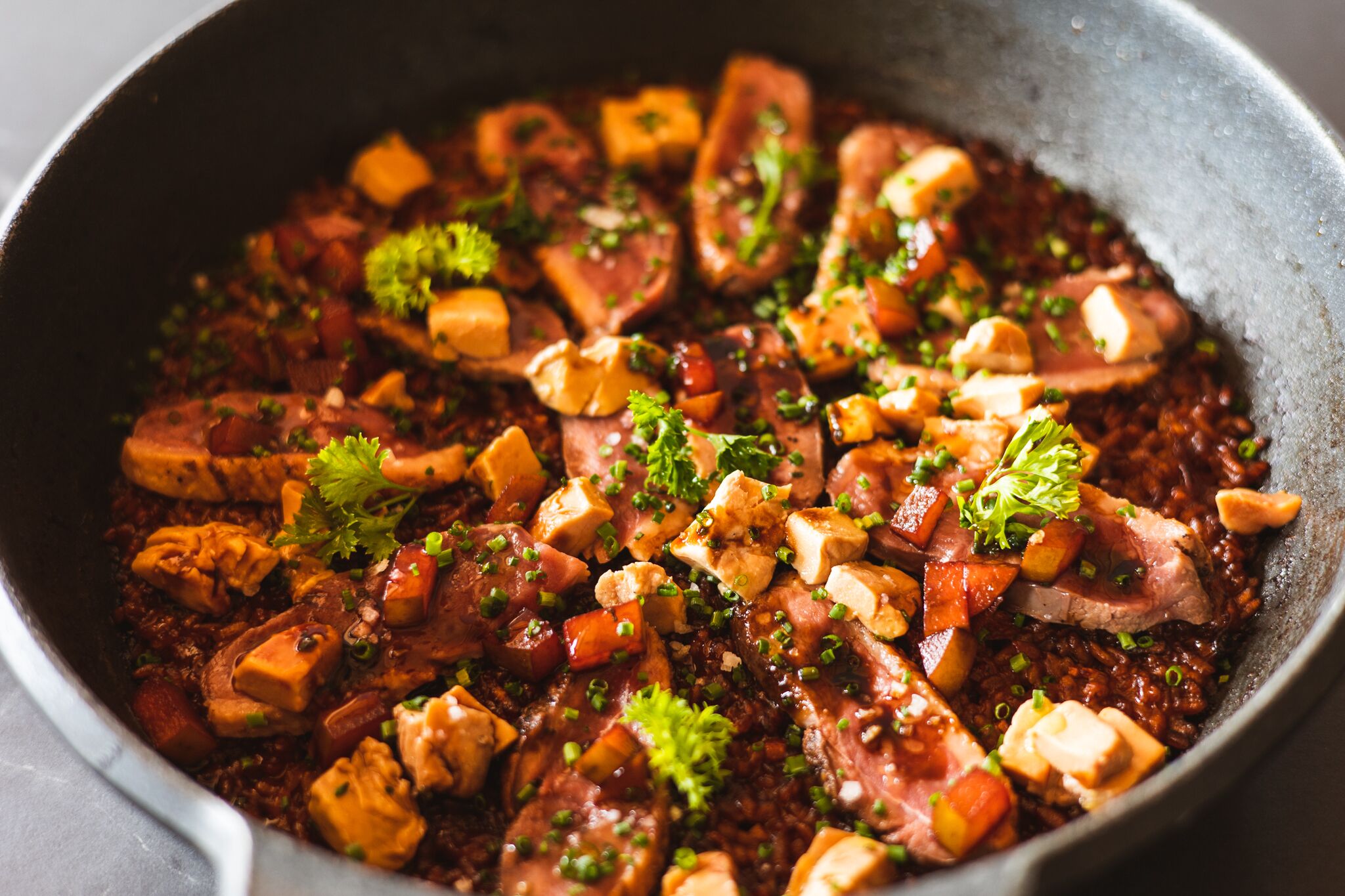 A close-up of a dish with various ingredients, including chunks of meat, vegetables, and garnishes.