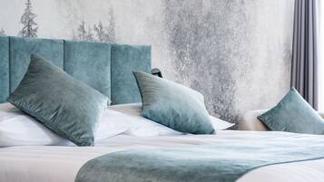 Una cama cuidadosamente tendida con un cabecero color aguamarina y almohadas a juego, frente a una pared con textura.
