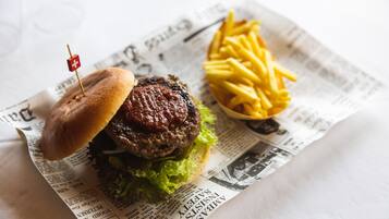 Un hamburger servi dans un pain, avec de la laitue et un petit drapeau planté sur le dessus, le tout présenté sur un journal.
