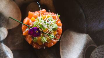 A close-up of a food dish with salmon, corn, sprouts, and a purple flower.