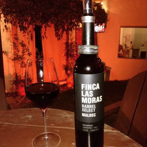 A bottle of Finca Las Moras wine with a glass of red wine on a table.