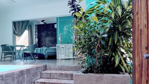 A modern interior with a staircase leading to a dining area, a bed, and a large plant. - Cabin in Arraial d'Ajuda with Private Pool (Arraial d'Ajuda)