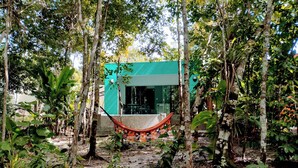 A modern building surrounded by dense forest, with a hammock in the foreground. - Cabin in Arraial d'Ajuda with Private Pool (Arraial d'Ajuda)