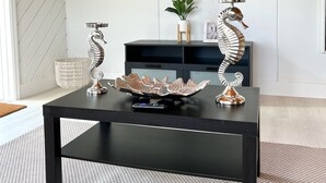 A modern living room with a black coffee table, two decorative seahorse sculptures, a woven basket, and a potted plant. - Bimini Vacation Apartment - Apt #4 (Bimini)
