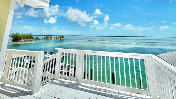 A wooden deck with a view of a clear blue sky and turquoise water. - Bimini Vacation Apartment - Apt #4 (Bimini)