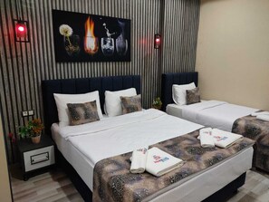 A hotel room with two beds, a large painting above the beds, and a nightstand with a lamp. - Marblue Hotel (Mardin)