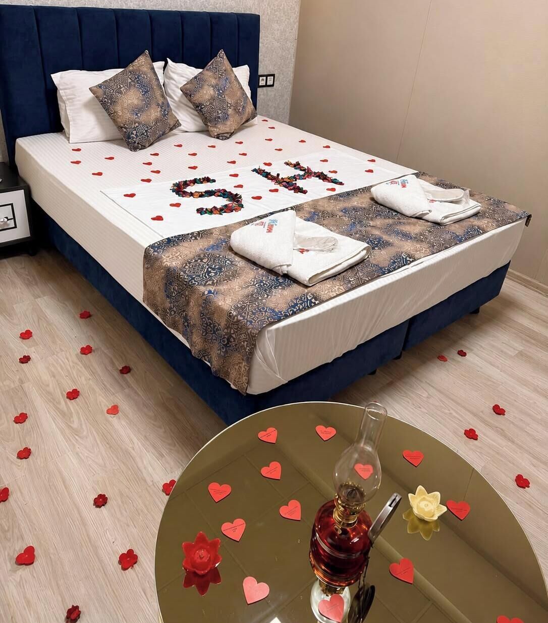A neatly made bed with a patterned bedspread, pillows, and a decorative heart-shaped arrangement of beads.