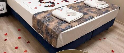 A neatly made bed with a patterned bedspread, pillows, and a decorative heart-shaped arrangement of beads.