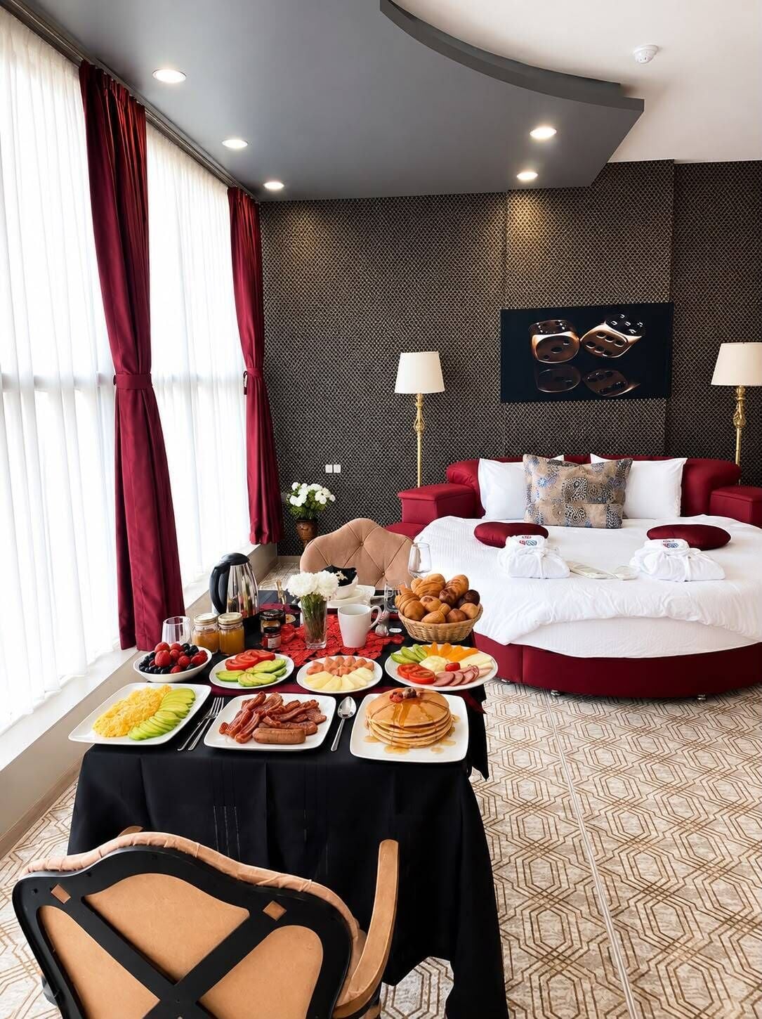 Habitación de hotel con una mesa de comedor dispuesta para el desayuno, una cama con ropa de cama roja y una obra de arte colgada en la pared.