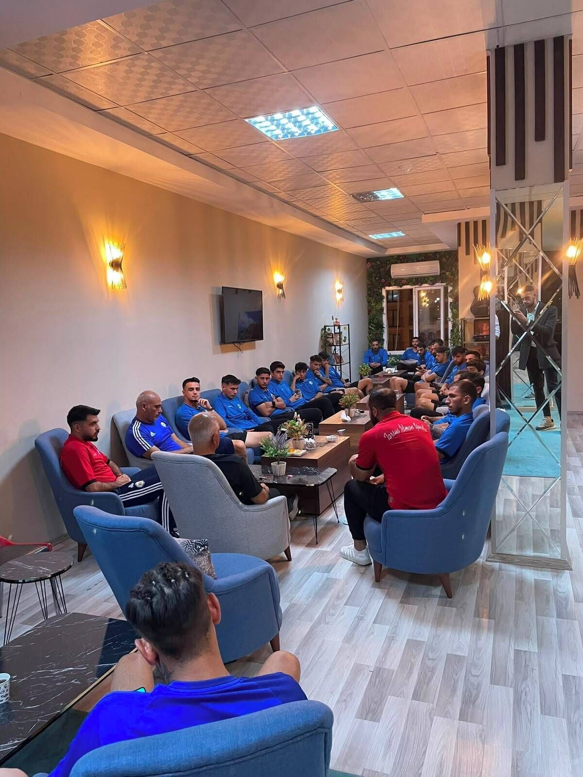 Una sala de conferencias con un grupo de personas sentadas alrededor de una mesa, participando en una reunión.