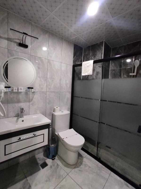 A modern bathroom with a large mirror, white sink, and a toilet. - Marblue Hotel (Mardin)
