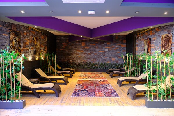 A spa area with stone walls, reclining chairs, and a patterned rug. - Side Mira Palace (Manavgat)