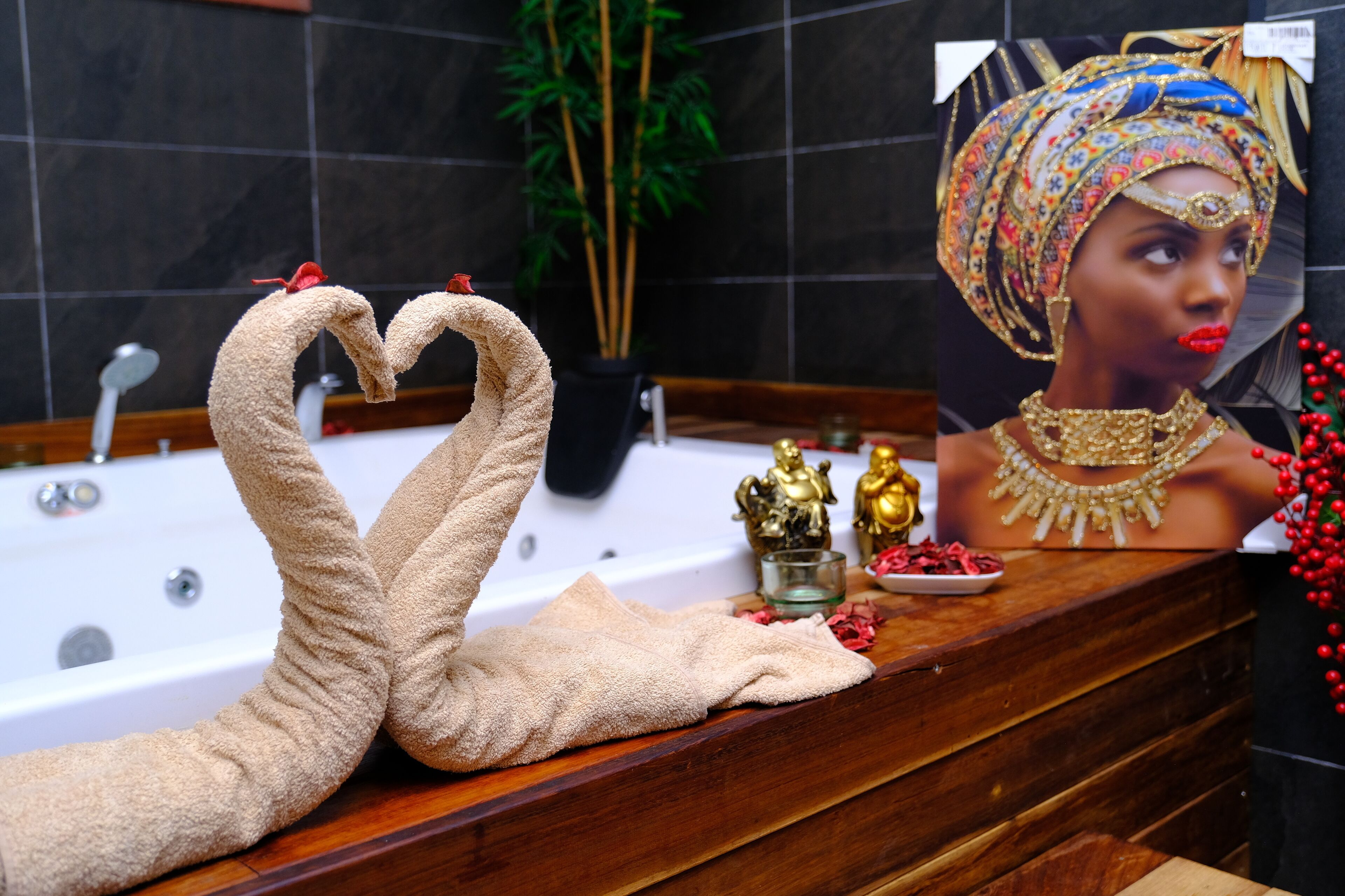 Un baño con bañera, espejo y una composición decorativa de toallas.