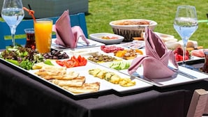 A table set outdoors with a variety of food and drinks, overlooking a scenic view. - Side Mira Palace (Manavgat)