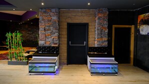 A room with a stone wall, a door, and two glass aquariums. - Side Mira Palace (Manavgat)