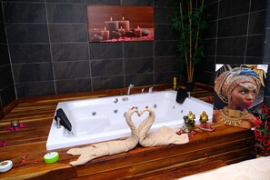 A wooden bathtub with a white interior, a framed picture on the wall, and a potted plant beside it. - Side Mira Palace (Manavgat)