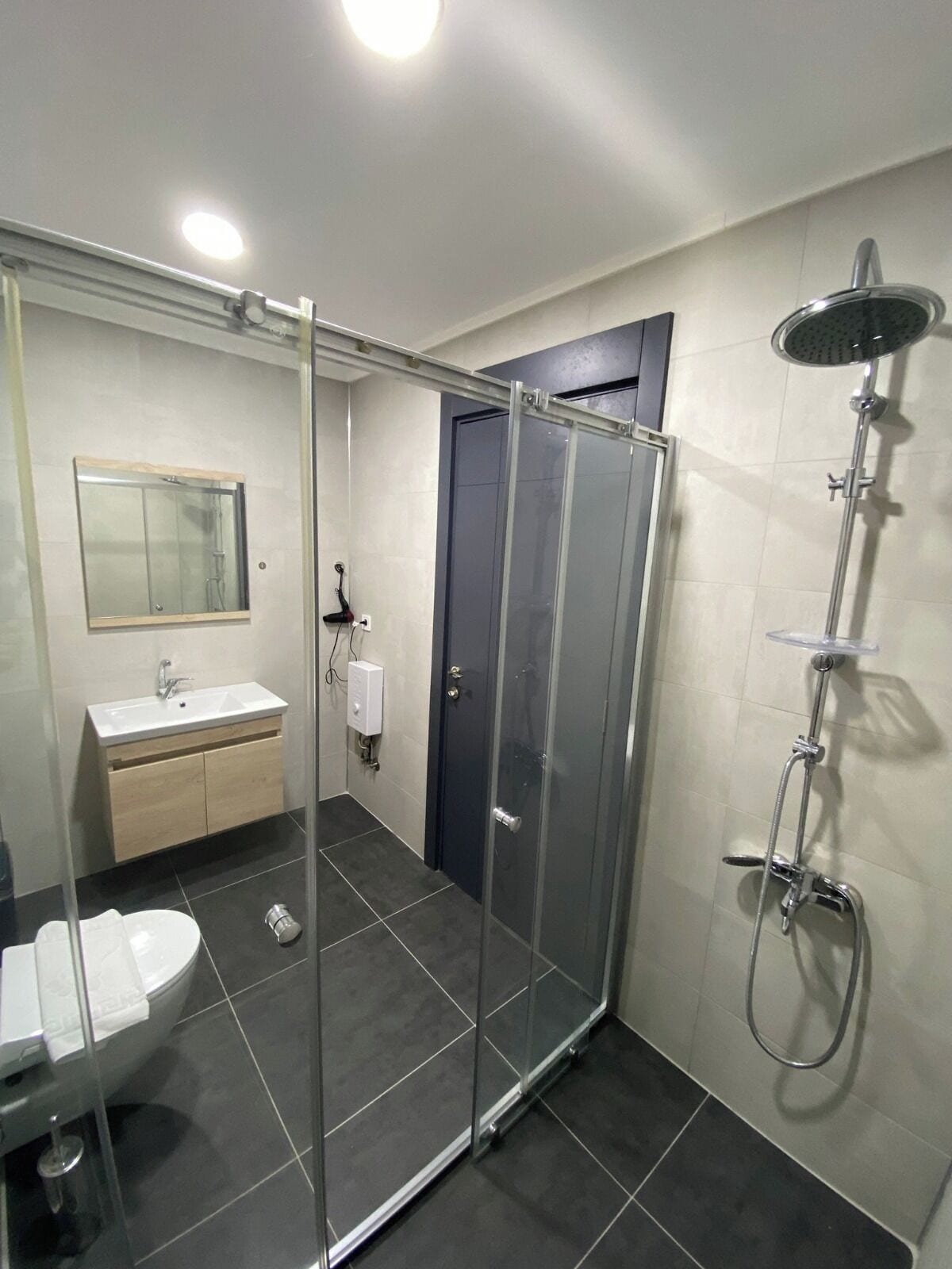 Un bagno moderno con doccia vetrata, lavandino con specchio e servizi igienici.