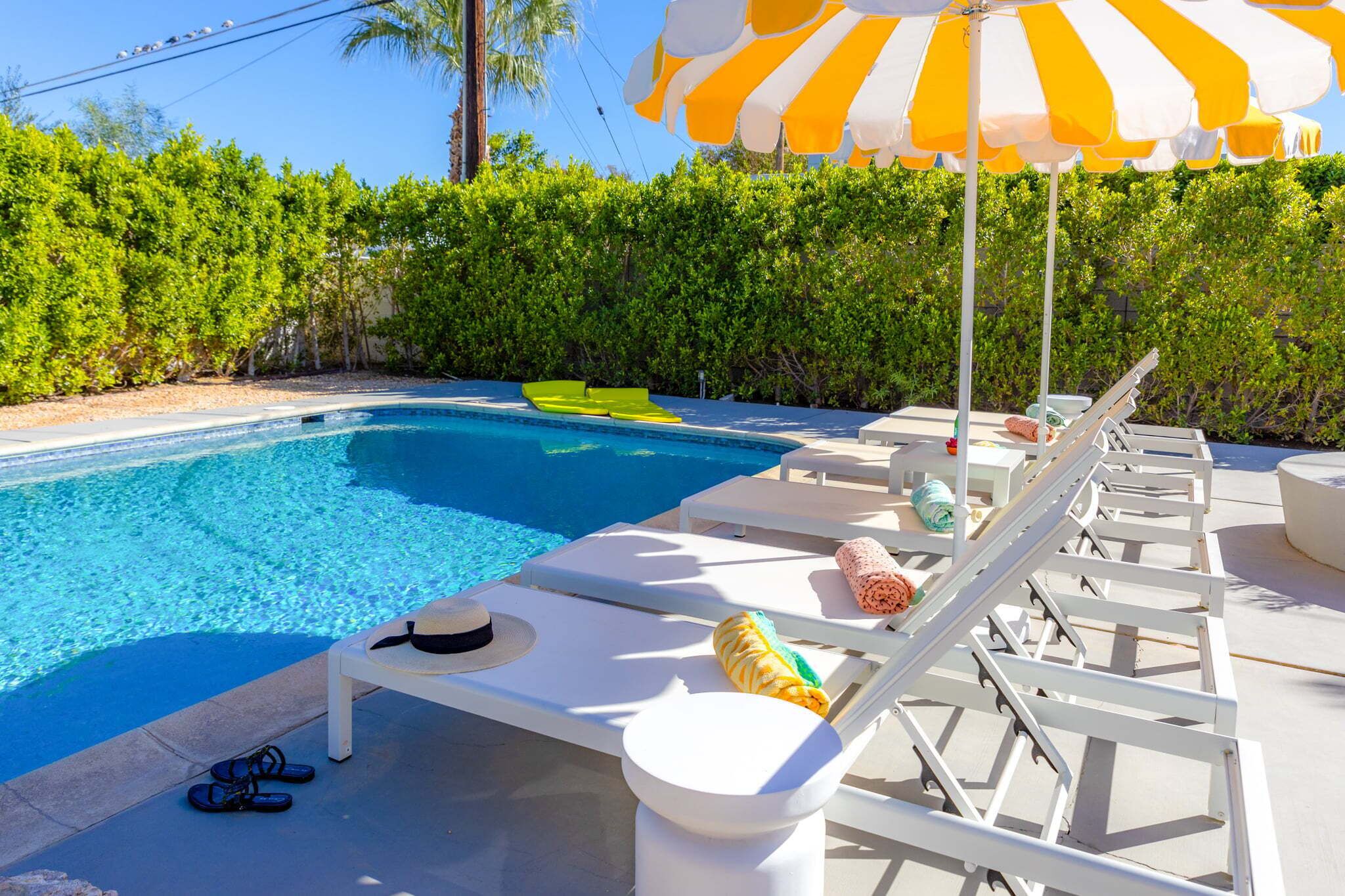 A swimming pool with lounge chairs and an umbrella.