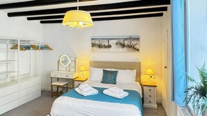 A bedroom with a bed, bedside tables, a dresser, a mirror, and a hanging light fixture. - This property is completely unique. (Scarborough)