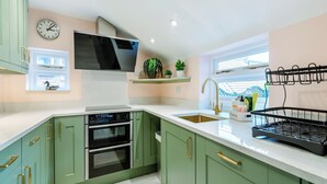 A modern kitchen with green cabinets, a stainless steel sink, and a built-in oven. - This property is completely unique. (Scarborough)