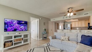 Una sala de estar con televisor, sofá y ventilador de techo.