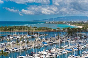 A marina filled with various boats and yachts, surrounded by greenery and a clear blue sky.