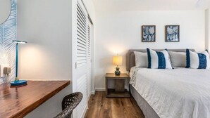 Een slaapkamer met een bed, nachtkastje met lamp, een houten bureau en een stoel.