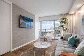 A modern living room with a sofa, a coffee table, and a balcony with outdoor furniture.