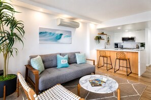 A modern living room with a grey sofa, a coffee table, and a large potted plant. - 429 · Ilikai Collection # 2. Sunset and ocean views! (Honolulu)