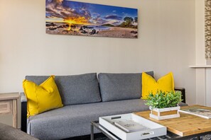 A living room with a grey sofa, yellow cushions, a coffee table with a plant, and a framed picture on the wall. - 1016 · Ilikai Collection # 4. Amazing views, beachfront. (Honolulu)