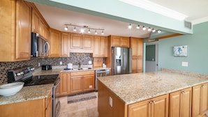 A kitchen with wooden cabinets, granite countertops, stainless steel appliances, and a backsplash. - Beach Blessings Edgewater 0602T2 Beautiful condo with Beautiful views! (Panama City Beach)
