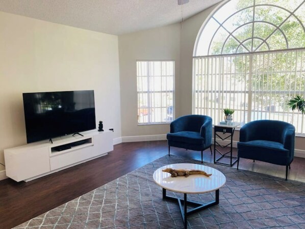 Relax in this stylish living room with a large flat-screen TV, arched window, and comfortable seating.