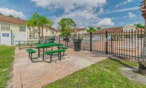 Enjoy a peaceful outdoor space with a picnic table and trash bin, surrounded by a secure black fence.