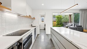 Una cocina moderna con armarios blancos, encimera negra y vistas al jardín trasero.