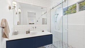 A modern bathroom with a white vanity, a glass shower enclosure, and a large mirror.