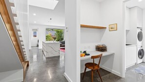A modern kitchen with a built-in washing machine, a wooden chair, and a small desk with a picture frame.