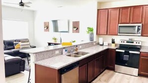 A modern kitchen with dark wooden cabinets, a stainless steel dishwasher, and a built-in oven. - Convenient 3-Bedroom Townhome with Full Garage (Nampa)
