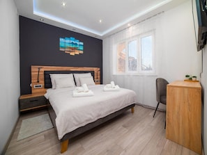 A modern bedroom with a bed, bedside table, and a desk.
