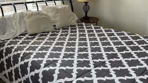 Un dormitorio con cama, ventana con persianas, lámpara de noche y adornos en la pared.