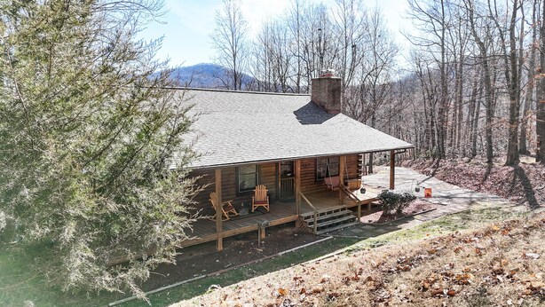 A log cabin with a porch, wooden chairs, and a fireplace. - Relax in Nature's Beauty: Private Log Cabin w/ two Spacious, Open Living Areas (Shipman)