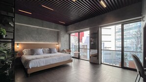 Un dormitorio moderno con una cama grande, techo de madera y vistas a la ciudad a través de amplios ventanales.