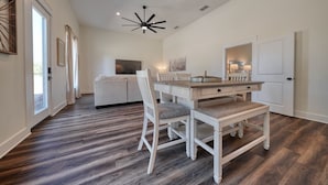 A spacious dining area with a wooden floor, white dining table, and chairs. - Brand New, Beautifully Appointed, Country Cottage! (Lindale)