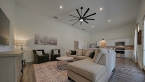 A spacious living room with a sectional sofa, two armchairs, a coffee table, and a patterned rug. A ceiling fan and recessed lighting are visible. - Brand New, Beautifully Appointed, Country Cottage! (Lindale)