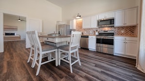 A modern kitchen with white cabinetry, a herringbone-patterned backsplash, and a central island with seating. - Brand New, Beautifully Appointed, Country Cottage! (Lindale)