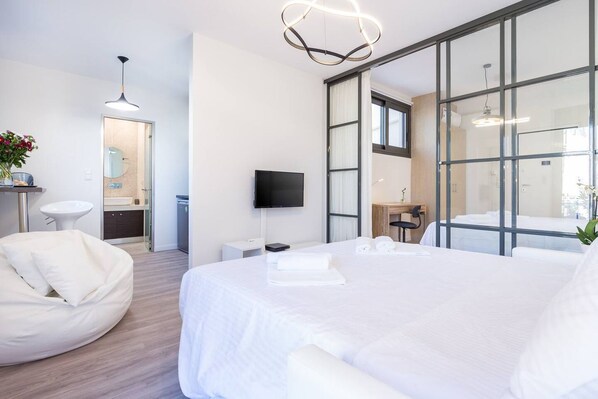 Camera d'albergo moderna con un letto grande, una TV a schermo piatto, una scrivania e un'area salotto.