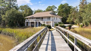 A house with a wooden deck leading to a porch, surrounded by trees and a marshy area. - Golden Isles Getaway -**ASK ABOUT SNOWBIRD SPECIALS** (Brunswick)