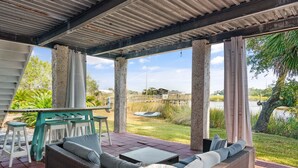 A covered outdoor seating area with wicker furniture and a view of a lake and greenery. - Golden Isles Getaway -**ASK ABOUT SNOWBIRD SPECIALS** (Brunswick)